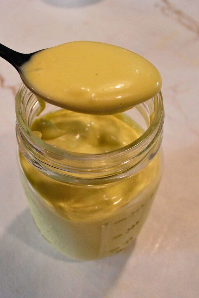 Close up of a spoonful of thick homemade mayonnaise showing creamy texture