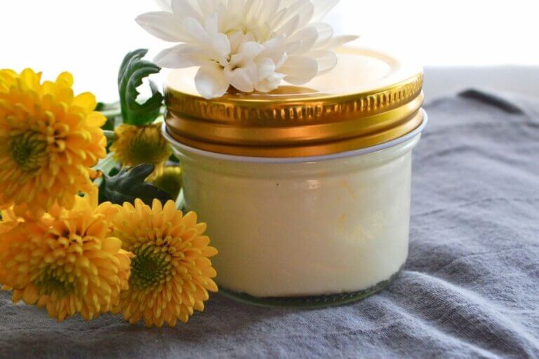 Homemade beef tallow lotion with calendula in a glass jar surrounded by flowers