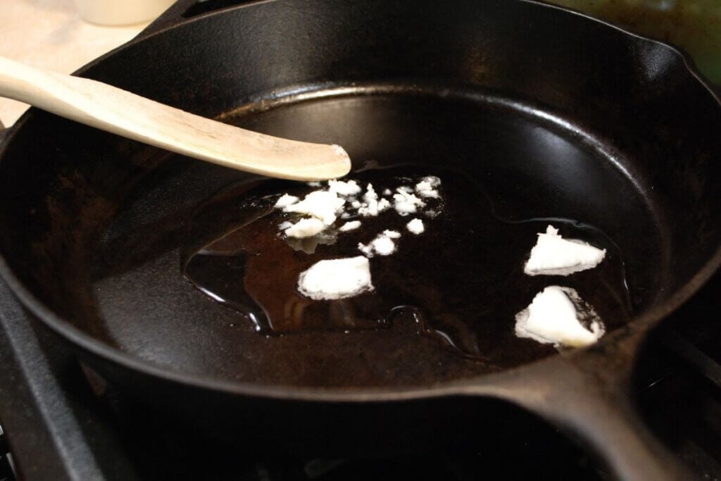 Beef fat melting in a cast iron skillet to make tallow