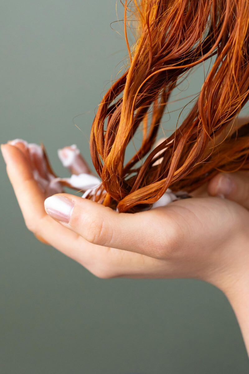 Applying beef tallow lotion to dry hair as a deep conditioning treatment.